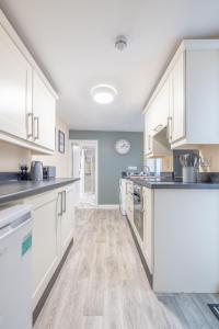 uma cozinha com armários brancos e piso de madeira em Violet Suite Apartments em Derry Londonderry