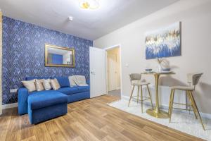 Violet Suite Apartments في ديري لندنديري: غرفة معيشة مع أريكة زرقاء وطاولة