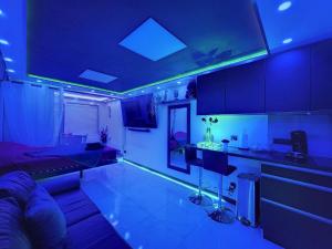 a living room with blue lighting and a kitchen with a couch at C12 Deluxe in Cap d'Agde