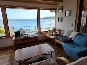 a living room with a blue couch and a large window at Puerto Austral in Puerto Varas