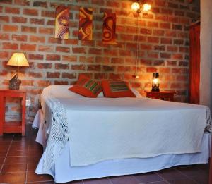 a bedroom with a white bed in a brick wall at Valdemoro Hosteria in Gualeguaychú