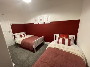 2 camas en una habitación con paredes rojas en Château by the Sea - Luxury hotel style 3 bed with hot tub, en Newbiggin-by-the-Sea