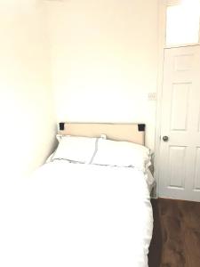 Cama blanca en habitación con puerta en PEACEFUL PLACE en Nottingham