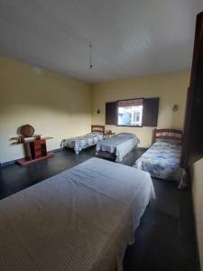 1 dormitorio con 3 camas, mesa y ventana en Casa ampla em Condomínio Águas de Olivença en Olivença