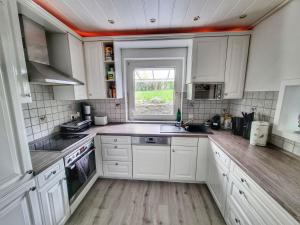 eine Küche mit weißen Schränken und einem Fenster in der Unterkunft Ferienhaus mit Sauna, Whirlpool und Garten in Wuppertal