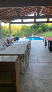een lange houten tafel met stoelen en een zwembad bij Sitio 2k Mairinque in Mairinque