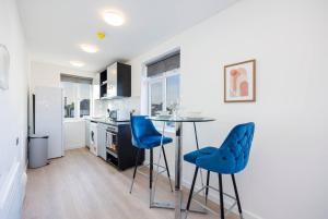 a kitchen with a table and two blue chairs at North West London Studio Apartment By AV Stays Short Lets London in London