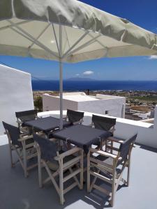 a table and chairs under an umbrella on a roof at Santorini Cave Suite in Éxo Goniá