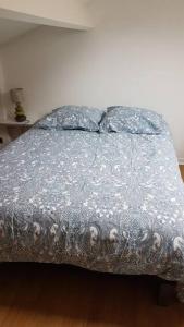 a bed with a silver comforter and two pillows at Appartement T2 face au golf in Buzet-sur-Tarn