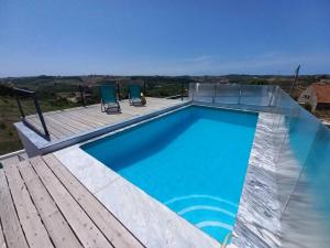 una piscina con 2 sillas azules en una terraza en Terraços da Serra, en Painho