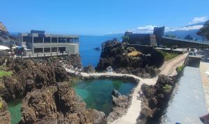 a building on a cliff next to the ocean at Fisherman's house in Porto Moniz