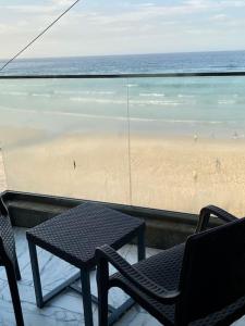 d'un balcon avec une table, des chaises et une plage. dans l'établissement L’écho des vagues, à Dakar