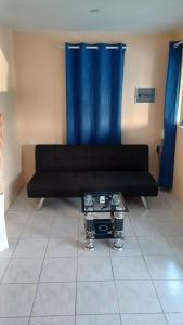 a black couch in a living room with blue curtains at Dushi Curaçaose appartement in Willemstad