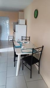 a dining room table with two chairs and a refrigerator at Dushi Curaçaose appartement in Willemstad