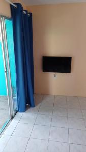 a living room with blue curtains and a tv at Dushi Curaçaose appartement in Willemstad