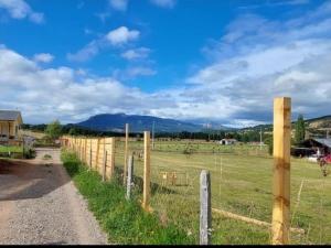 a fence in a field with mountains in the background at cabaña los teros in Coihaique