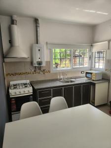 a kitchen with a sink and a counter with chairs at MAKTUB DEPARTAMENTOS Y HABITACIONES in Alta Gracia