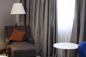 エレバンにあるRadisson BLU Hotel Yerevanのカーテン付きの部屋(椅子、ランプ付)