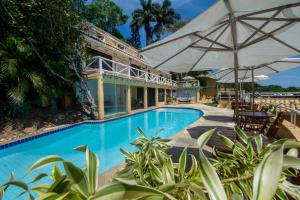 una piscina al aire libre con sombrillas y un complejo en Pousada e Spa Villa Mercedes by Latitud Hoteles, en Búzios