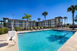 une piscine avec des chaises et des palmiers dans un hôtel dans l'établissement SureStay Hotel by Best Western Clermont Theme Park West, à Kissimmee