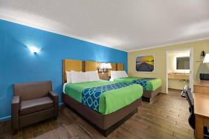 a hotel room with two beds and a chair at SureStay Hotel by Best Western Clermont Theme Park West in Kissimmee
