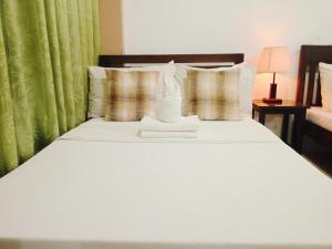 1 dormitorio con cama blanca y cortina verde en Mariana Condotel, en Puerto Princesa City