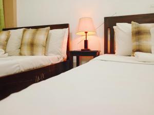 2 camas en una habitación con una lámpara en una mesa en Mariana Condotel, en Puerto Princesa City
