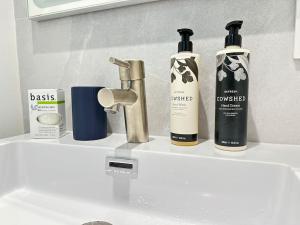 um lavatório de casa de banho com três garrafas de produtos para o cabelo em Coconut Grove Mid-Century Jungle Oasis em Miami