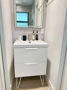 a bathroom with a white sink and a mirror at Coconut Grove Mid-Century Jungle Oasis in Miami