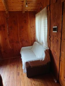 uma cama num quarto de madeira com uma janela em La Cabañita em Tanti