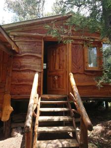 uma cabana de madeira com escadas que levam à porta em La Cabañita em Tanti