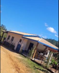 a house with a fence next to a dirt road at Chale Jatoba Monteiro Lobato in Monteiro Lobato