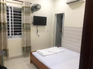 a bedroom with a bed with a television and a window at Homestay 05 in Vung Tau