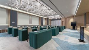 EVEN Hotel Zhongshan City Center, an IHG Hotel في تشونغشان: قاعة اجتماعات مع طاولات وكراسي خضراء