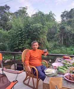Ein Mann, der mit einem Glas Wein am Tisch sitzt. in der Unterkunft Lunda Orchid Resort in Suan Phung