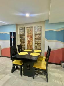 comedor con mesa negra y sillas amarillas en #3 Luxury Suite en Puerto Santa Ana, en Guayaquil