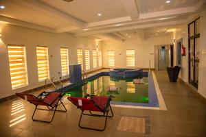 a swimming pool in a house with two chairs at Abada Luxury Hotel and Suites in Onitsha