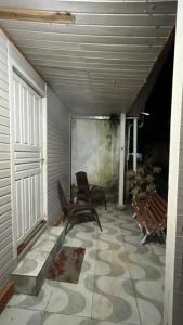 un porche con una silla y un banco en un patio en Casa Ágata, en Cidreira