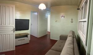 een woonkamer met een bank en een flatscreen-tv bij Casa Ágata in Cidreira