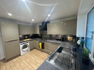 a kitchen with a sink and a washing machine at Charming room in stylish house in Milton Keynes