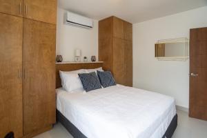 um quarto com uma grande cama branca e armários de madeira em Viñedos del Mar em Ensenada