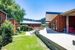 una terraza de madera con bancos en un patio en Hot Water Beach TOP 10 Holiday Park en Hotwater Beach