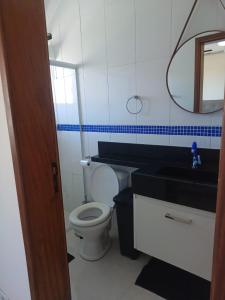 La salle de bains est pourvue de toilettes, d'un lavabo et d'un miroir. dans l'établissement Casa mar sol e piscina, à Peruíbe
