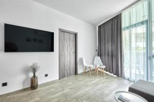 a living room with a tv on a white wall at Paradise Apartments Primorsko in Primorsko