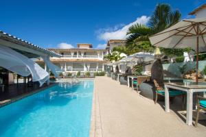 a resort with a swimming pool with tables and umbrellas at Pousada Aroma do Mar by Latitud Hoteles in Búzios