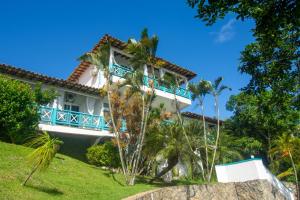 a house with a blue balcony and palm trees at Pousada Aroma do Mar by Latitud Hoteles in Búzios