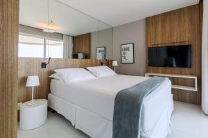 1 dormitorio con 1 cama blanca grande y TV de pantalla plana en Flat Ocean View, en Río de Janeiro