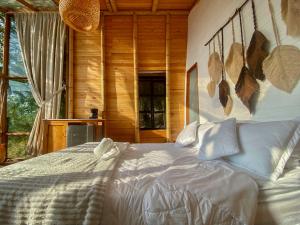 1 dormitorio con cama blanca frente a una ventana en NaturalMente Glamping, en San Antonio del Tequendama