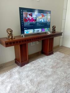 einen Schreibtisch mit einem TV darüber in der Unterkunft Aconchego Apartamentos da Serra in Canela