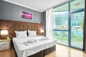a bedroom with a large bed and a large window at Paradise Apartments Primorsko in Primorsko +27 photos